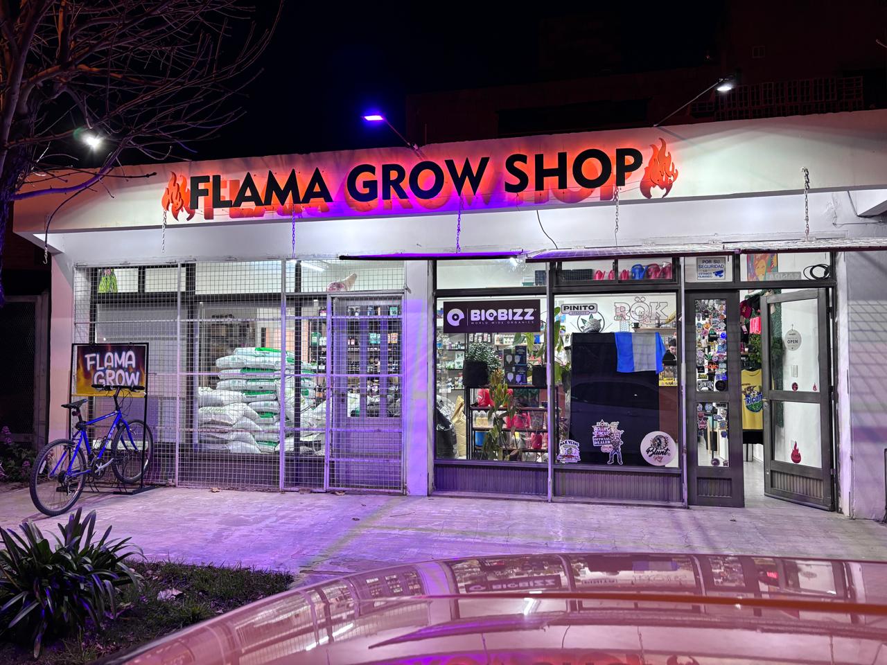 Frente de Flama Grow Shop de noche con el cartel iluminado